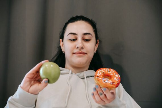 kobieta trzymająca pączek i jabłko